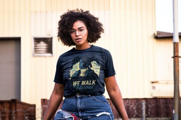 Mockup of a Tattoed Black Woman with Curly Hair Wearing a Plus Size T-shirt in City Outdoors Wearing Glasses B